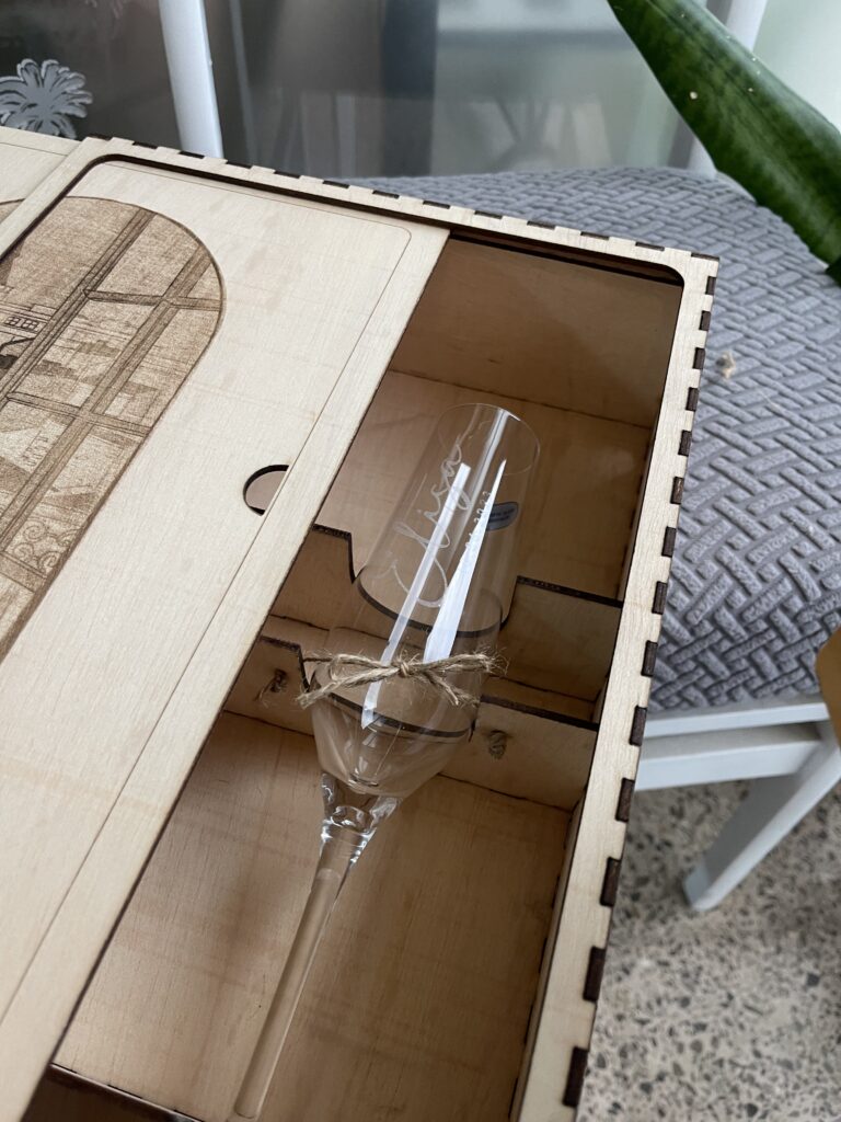 Caja de madera con tapa deslizante grabada y una copa en su interior