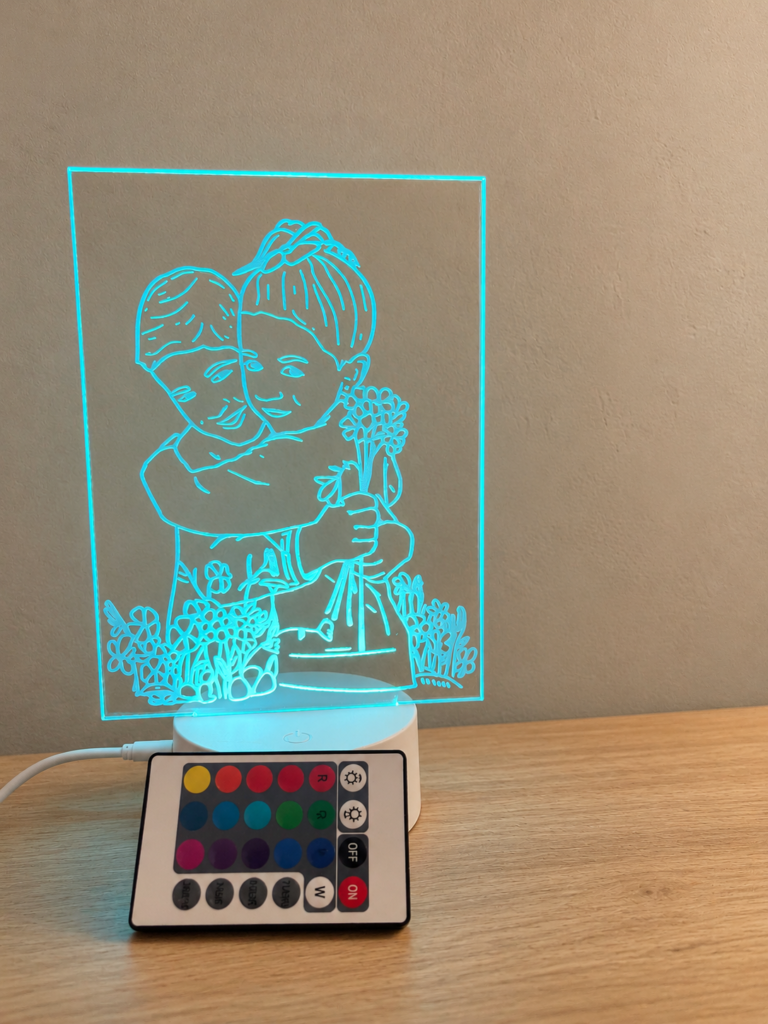 Lámpara de metacrilato iluminada en azul con ilustración de una pareja y mando